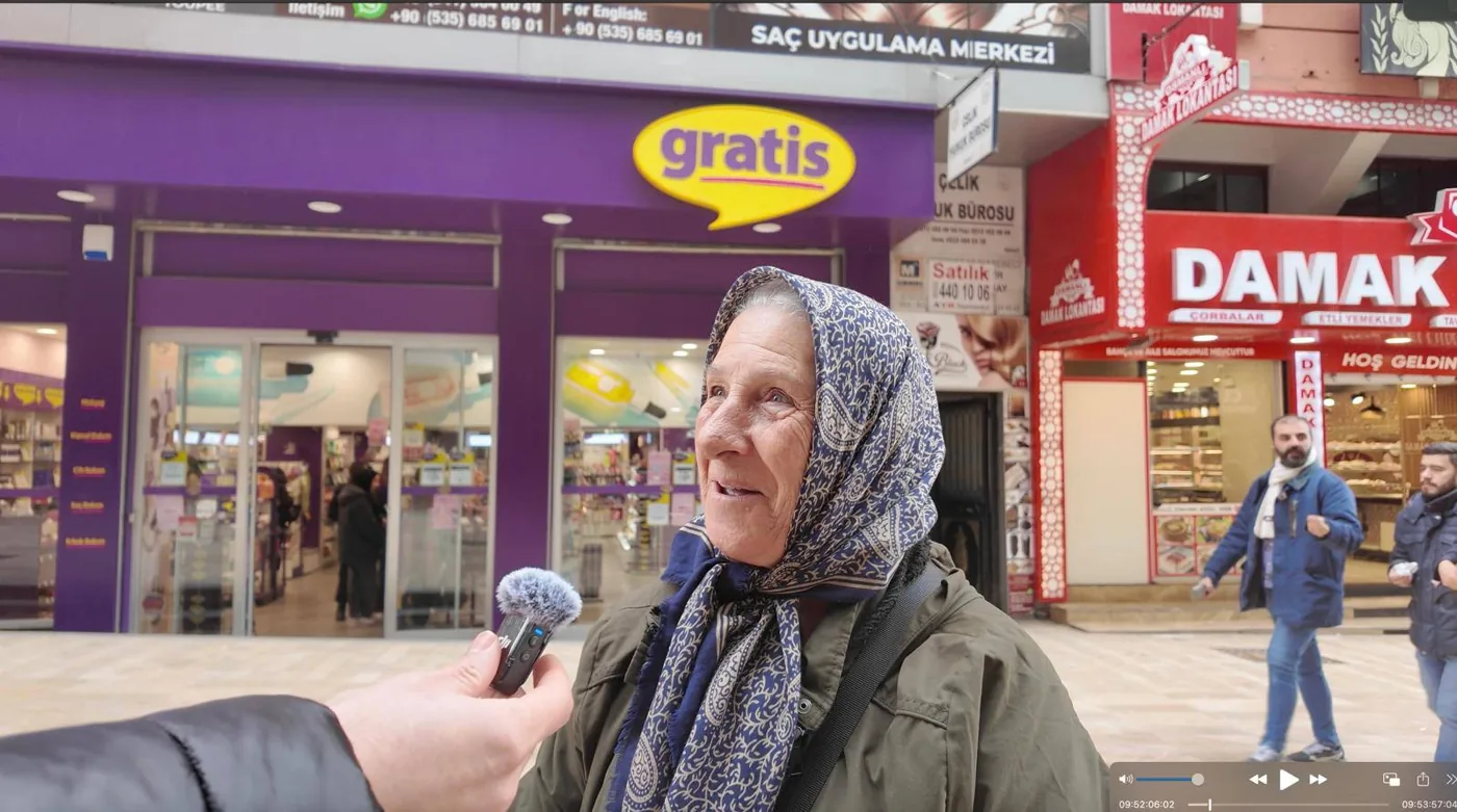 Mağaza önünde mikrofona konuşan yaşlı kadın; alıcı yorumu olarak sunulmuyor · müşterinin sağladığı fotoğraf